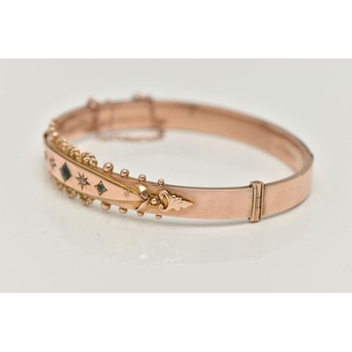 119 - A 9CT GOLD EDWARDIAN BANGLE, rose gold hinged bangle, set with three green stones assessed as two sm... 