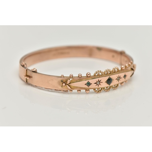 119 - A 9CT GOLD EDWARDIAN BANGLE, rose gold hinged bangle, set with three green stones assessed as two sm... 