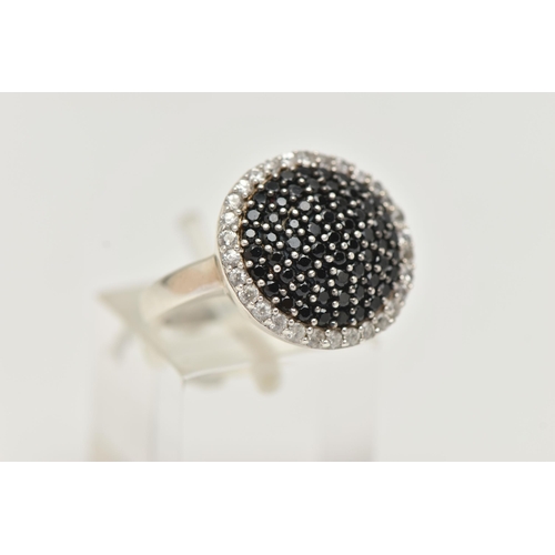 35 - A GEM SET CLUSTER RING, comprised of black circular cut stones, pave set with a surround of colourle... 