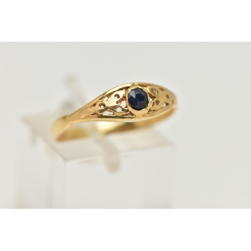 67 - A YELLOW METAL SAPPHIRE RING, set with a single circular cut dark blue sapphire, open work surround,... 