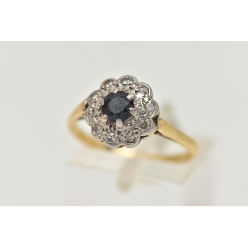 95 - A YELLOW METAL SAPPHIRE AND DIAMOND CLUSTER RING, set with a central circular cut blue sapphire with... 