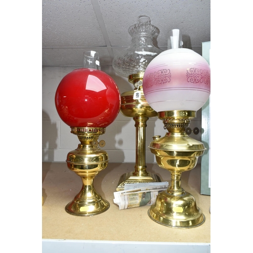 601 - THREE BRASS OIL LAMPS, with shades and chimneys, the tallest with column style base approximately 67... 