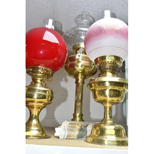 601 - THREE BRASS OIL LAMPS, with shades and chimneys, the tallest with column style base approximately 67... 