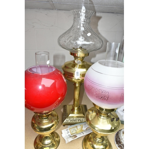 601 - THREE BRASS OIL LAMPS, with shades and chimneys, the tallest with column style base approximately 67... 