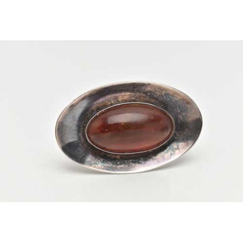 11 - A DANISH SILVER AND AMBER BROOCH, oval form concaved brooch, centrally set with an oval cabochon amb... 