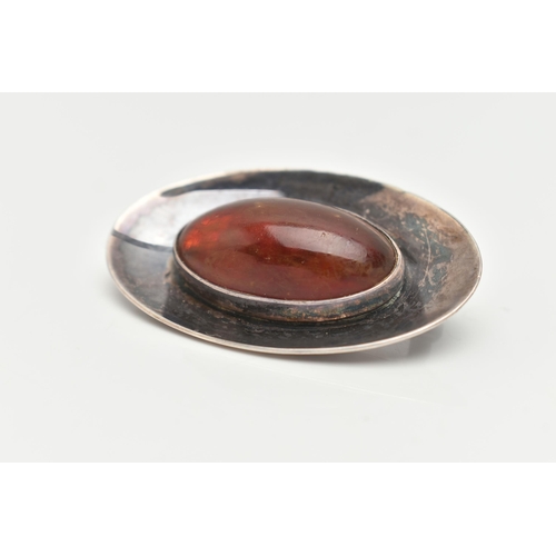 11 - A DANISH SILVER AND AMBER BROOCH, oval form concaved brooch, centrally set with an oval cabochon amb... 