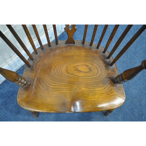 1223 - A REPRODUCTION ELM SEATED WHEEL BACK WINDSOR ARMCHAIR, with turned supports and legs, united by a cr... 