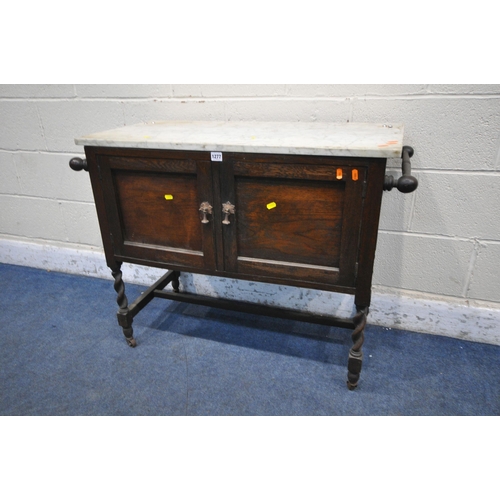 1277 - AN EARLY 2OTH CENTURY OAK MARBLE TOP WASH STAND, with twin towel rails, double doors, on barley twis... 