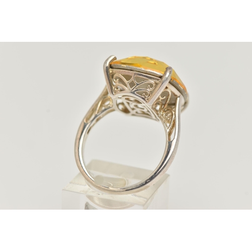 18 - A DRESS RING, designed as a large yellow gemstone assessed as quartz, within a four claw setting, st... 