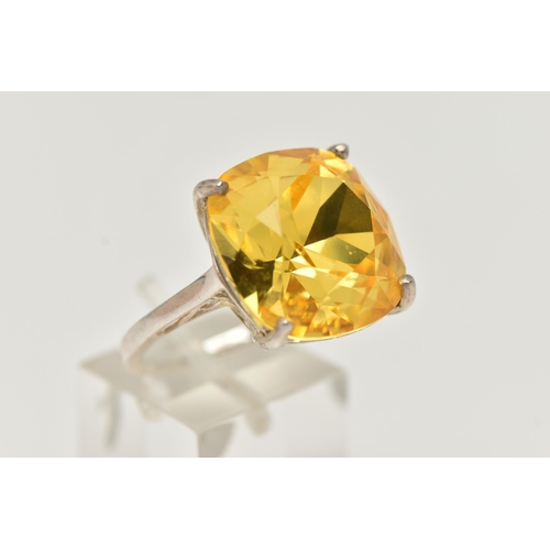 18 - A DRESS RING, designed as a large yellow gemstone assessed as quartz, within a four claw setting, st... 