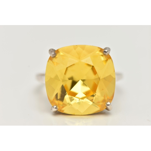 18 - A DRESS RING, designed as a large yellow gemstone assessed as quartz, within a four claw setting, st... 