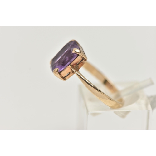 25 - A YELLOW METAL GEM SET RING, rectangular cut purple stone assessed as amethyst, prong set in yellow ... 