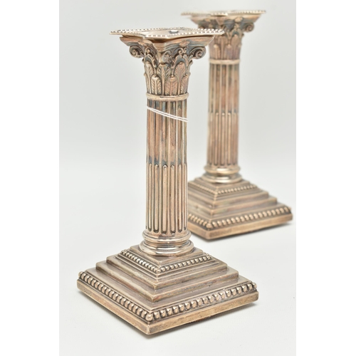 79 - A PAIR OF LATE VICTORIAN SILVER CANDLE STICKS, Corinthian columns scroll leaf detail, on square step... 