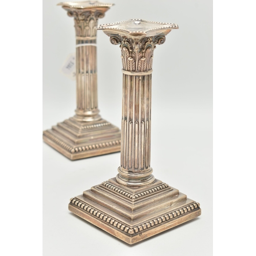 79 - A PAIR OF LATE VICTORIAN SILVER CANDLE STICKS, Corinthian columns scroll leaf detail, on square step... 