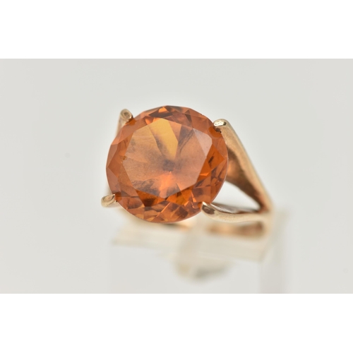 89 - A 9CT GOLD DRESS RING, a large round cut orange stone assessed as synthetic sapphire, set in a four ... 