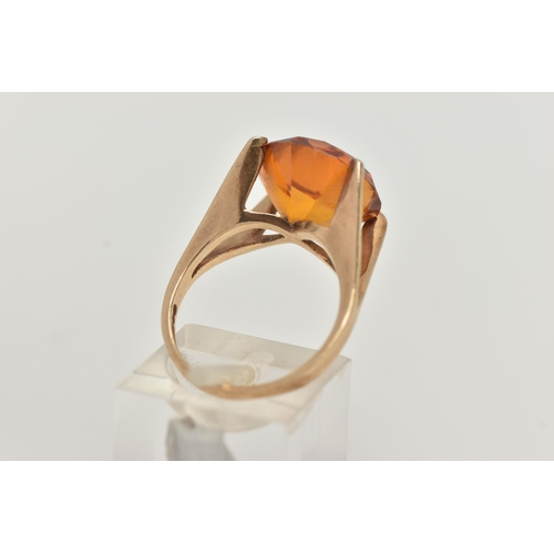 89 - A 9CT GOLD DRESS RING, a large round cut orange stone assessed as synthetic sapphire, set in a four ... 