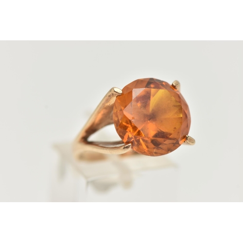 89 - A 9CT GOLD DRESS RING, a large round cut orange stone assessed as synthetic sapphire, set in a four ... 