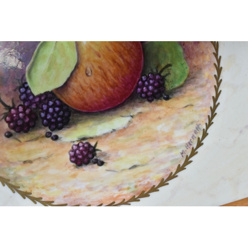 416 - TWO FRAMED HAND PAINTED CERAMIC PLAQUES, signed M. Harnett, painted with fruit in a central circular... 