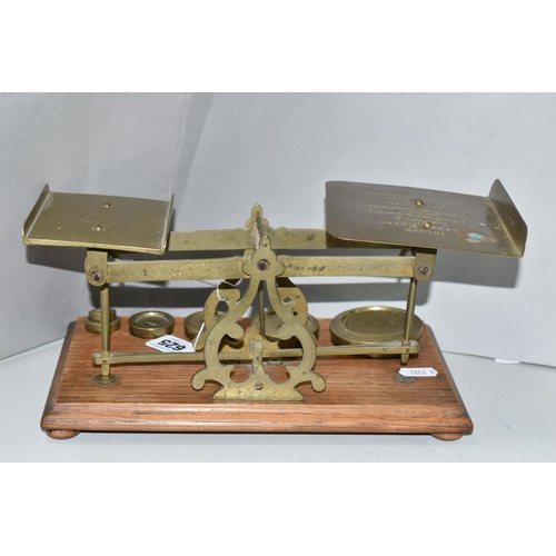 625 - A SET OF BRASS POSTAL SCALES, mounted on wooden plinth, no makers marks, complete with six brass wei... 