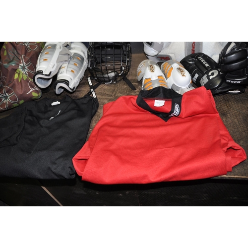 1059 - A BAG CONTAINING ICE HOCKEY CLOTHING, PADS AND HELMET by Reebok, CCM, Bauer, Sherwood etc T shirts a... 