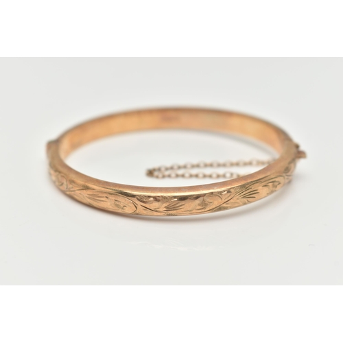 29 - A CHILDS 9CT YELLOW GOLD HINGED BANGLE, hollow bangle with an engraved foliate pattern, push piece i... 