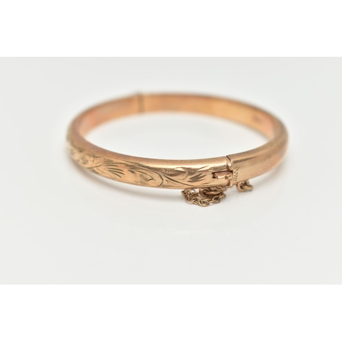 29 - A CHILDS 9CT YELLOW GOLD HINGED BANGLE, hollow bangle with an engraved foliate pattern, push piece i... 