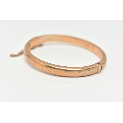 29 - A CHILDS 9CT YELLOW GOLD HINGED BANGLE, hollow bangle with an engraved foliate pattern, push piece i... 