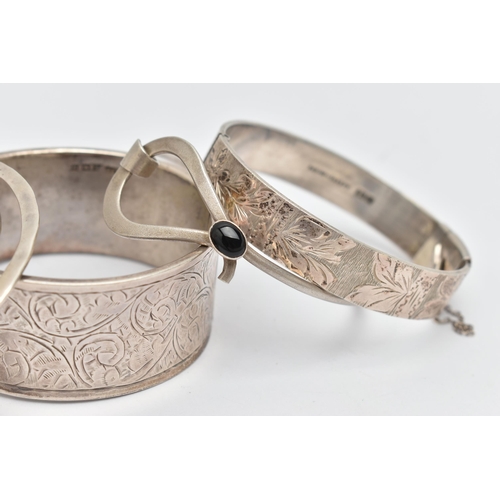 109 - THREE SILVER BANGLES AND TWO WHITE METAL BANGLES, the first a silver wide hinged bangle, with scroll... 