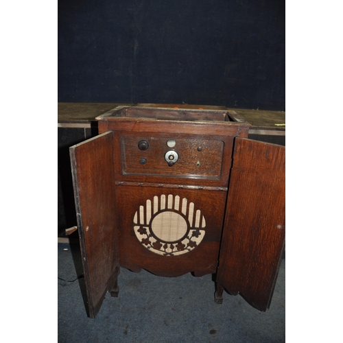 1054 - A VINTAGE VALVE RADIO IN A LIDDED OAK CABINET with a battery inside width 54cm depth 35cm height 91c... 