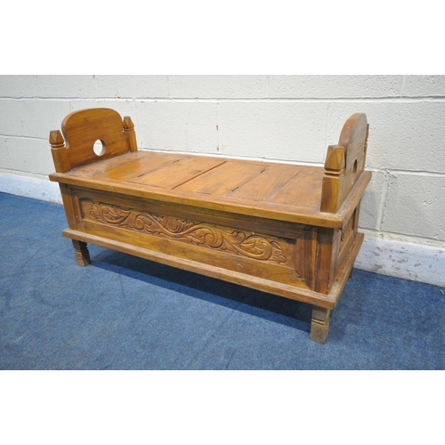 1202 - A 20TH CENTURY HARDWOOD BENCH, the twin arched ends with finials, a double hinged storage compartmen... 