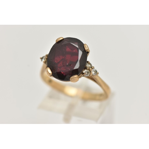 73 - A 9CT GOLD GARNET RING, a large oval cut garnet, approximate length 13mm, flanked with six circular ... 