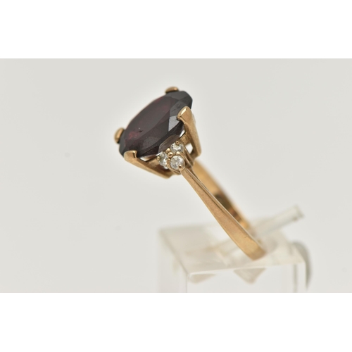 73 - A 9CT GOLD GARNET RING, a large oval cut garnet, approximate length 13mm, flanked with six circular ... 