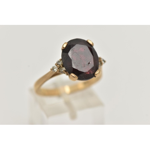 73 - A 9CT GOLD GARNET RING, a large oval cut garnet, approximate length 13mm, flanked with six circular ... 