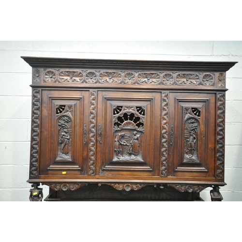 1202 - A CARVED OAK BRETON SIDEBOARD, fitted with an arrangement of five panel doors, depicting humans in v... 