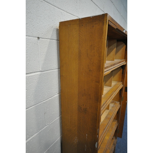 1216 - A GOVERNMENT ISSUE STAVERTON OAK BOOKCASE, with five rise and fall doors, enclosing an arrangement o... 