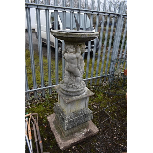 1005 - A LARGE WEATHERED COMPOSITE SUN DIAL, depicting three nude putto's holding the top aloft, on a squar... 