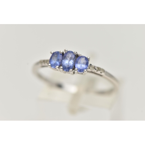 25 - A 14CT WHITE GOLD TANZANITE AND DIAMOND RING, three oval cut tanzanite, each four claw set, small si... 