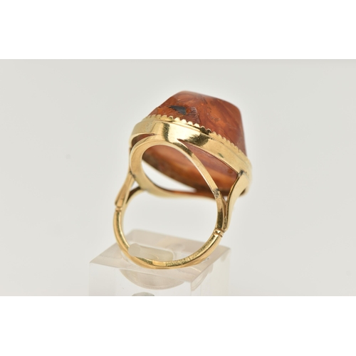 27 - A PRESSED AMBER RING, designed as a large oval piece of pressed amber within a collet style setting,... 