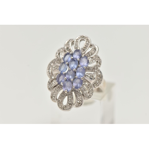 62 - A 14CT WHITE GOLD TANZANITE AND DIAMOND DRESS RING, designed as a central cluster of oval cut tanzan... 