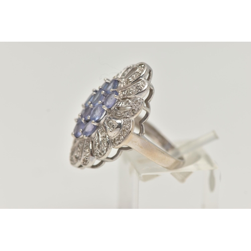 62 - A 14CT WHITE GOLD TANZANITE AND DIAMOND DRESS RING, designed as a central cluster of oval cut tanzan... 