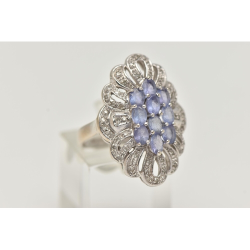 62 - A 14CT WHITE GOLD TANZANITE AND DIAMOND DRESS RING, designed as a central cluster of oval cut tanzan... 