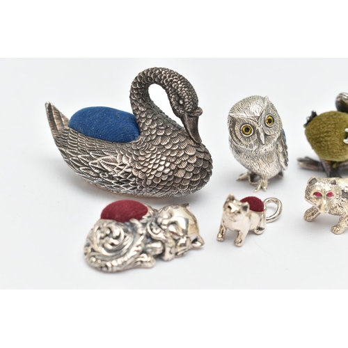 132 - FIVE PIN CUSHIONS AND A FIGURINE, to include a silver swan pin cushion, hallmarked 'Ari D Norman' Lo... 