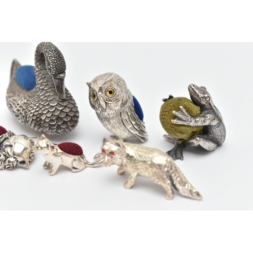 132 - FIVE PIN CUSHIONS AND A FIGURINE, to include a silver swan pin cushion, hallmarked 'Ari D Norman' Lo... 