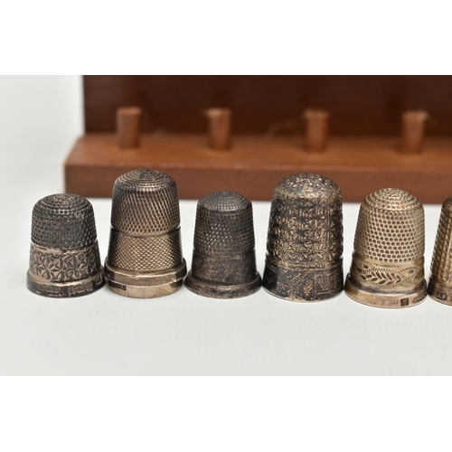 147 - A SELECTION OF SILVER THIMBLES AND TWO DISPLAY SHELVES, to include twenty-one thimbles, various desi... 