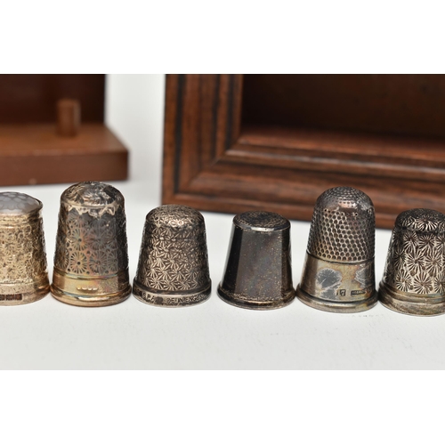 147 - A SELECTION OF SILVER THIMBLES AND TWO DISPLAY SHELVES, to include twenty-one thimbles, various desi... 