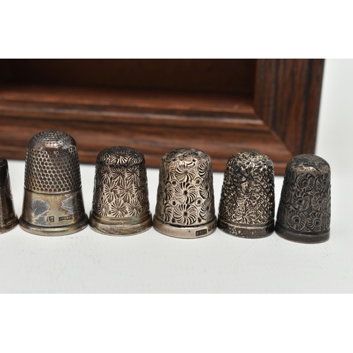 147 - A SELECTION OF SILVER THIMBLES AND TWO DISPLAY SHELVES, to include twenty-one thimbles, various desi... 