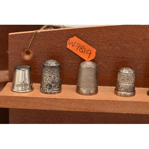 148 - A SELECTION OF SILVER THIMBLES AND TWO DISPLAY SHELVES, to include twenty-two thimbles, various desi... 