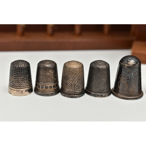 148 - A SELECTION OF SILVER THIMBLES AND TWO DISPLAY SHELVES, to include twenty-two thimbles, various desi... 