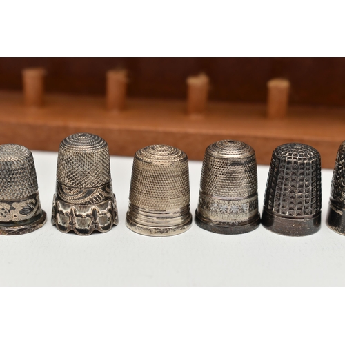 148 - A SELECTION OF SILVER THIMBLES AND TWO DISPLAY SHELVES, to include twenty-two thimbles, various desi... 