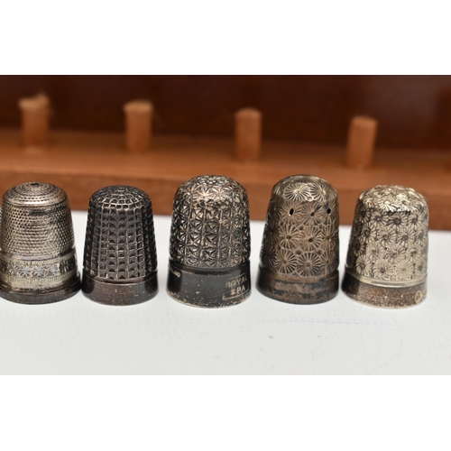 148 - A SELECTION OF SILVER THIMBLES AND TWO DISPLAY SHELVES, to include twenty-two thimbles, various desi... 